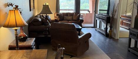 A cozy living room with a wooden dining table, a sofa, and a TV stand.