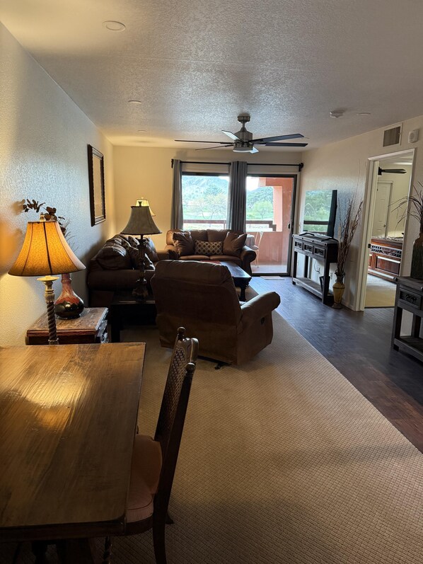 A cozy living room with a wooden dining table, a sofa, and a TV stand. - CASA RANCHERO: Cowboy up, golf course view. (Phoenix, Arizona)