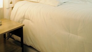 A neatly made bed with a tufted headboard, a bedside table, and a lamp.
