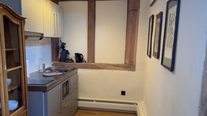 Une cuisine étroite avec des meubles de rangement en bois, un four encastré et une fenêtre au-dessus de l’évier.