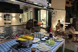 Un comedor con una mesa dispuesta para una comida, incluyendo una olla caliente, diferentes acompañamientos y bebidas.
