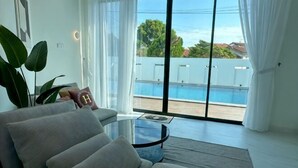 Un saló modern amb un sofà, una taula de centre de vidre i vista a una piscina.