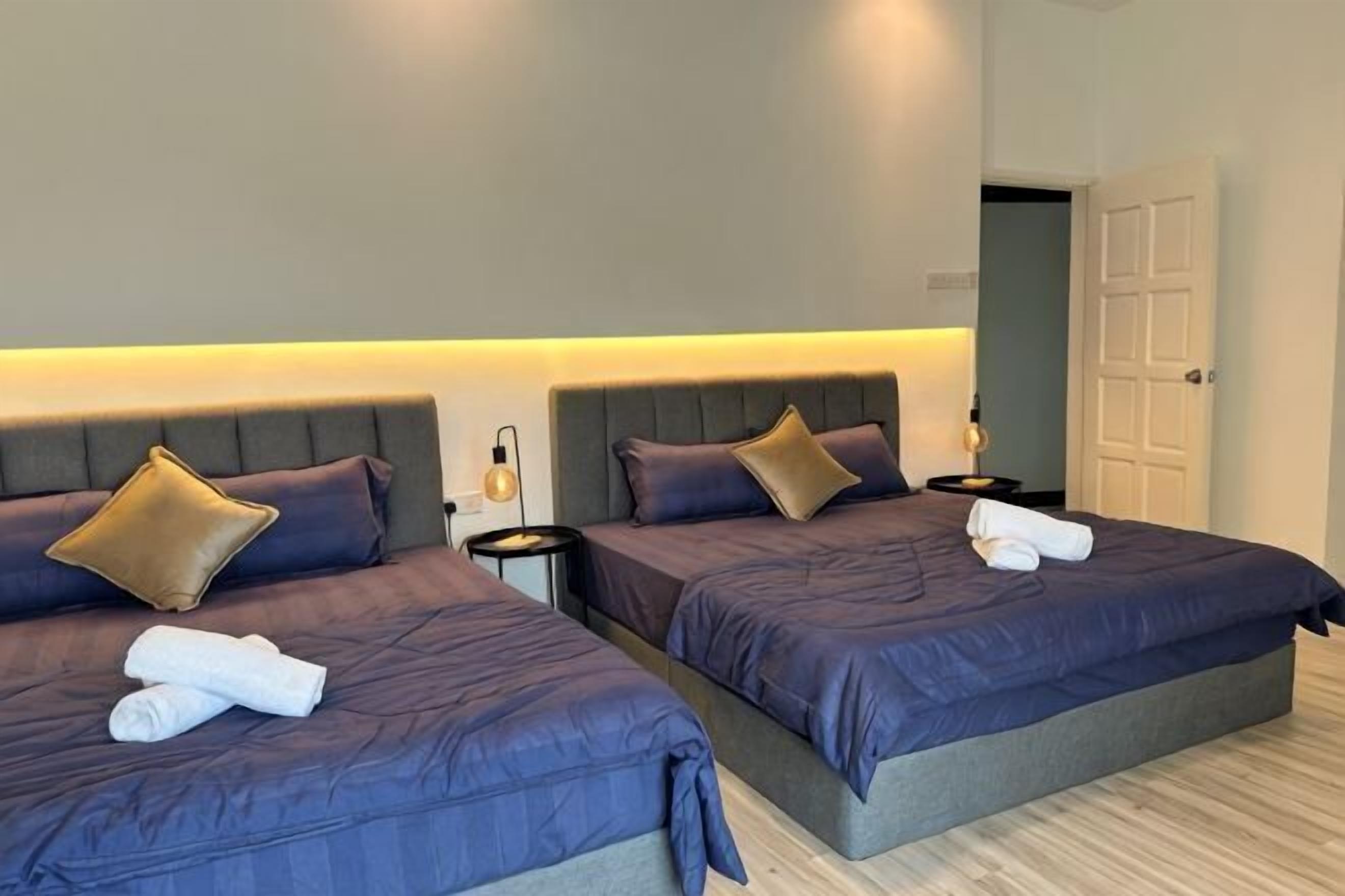 Two twin beds with headboards, bedside tables, and a door in the background.