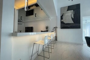 Una cucina moderna con angolo bar, piani in marmo bianco e sgabelli da bar.