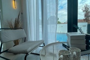Ein Balkon mit Stuhl, Tisch und Blick auf einen Swimmingpool.
