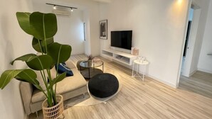 Un saló modern amb un sofà, una taula baixa, una televisió i una planta gran.
