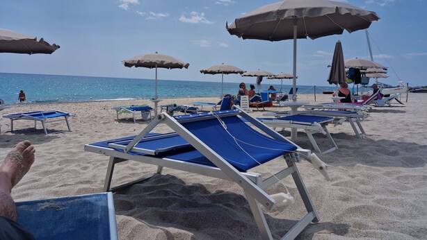 A beach with sun loungers and umbrellas.
