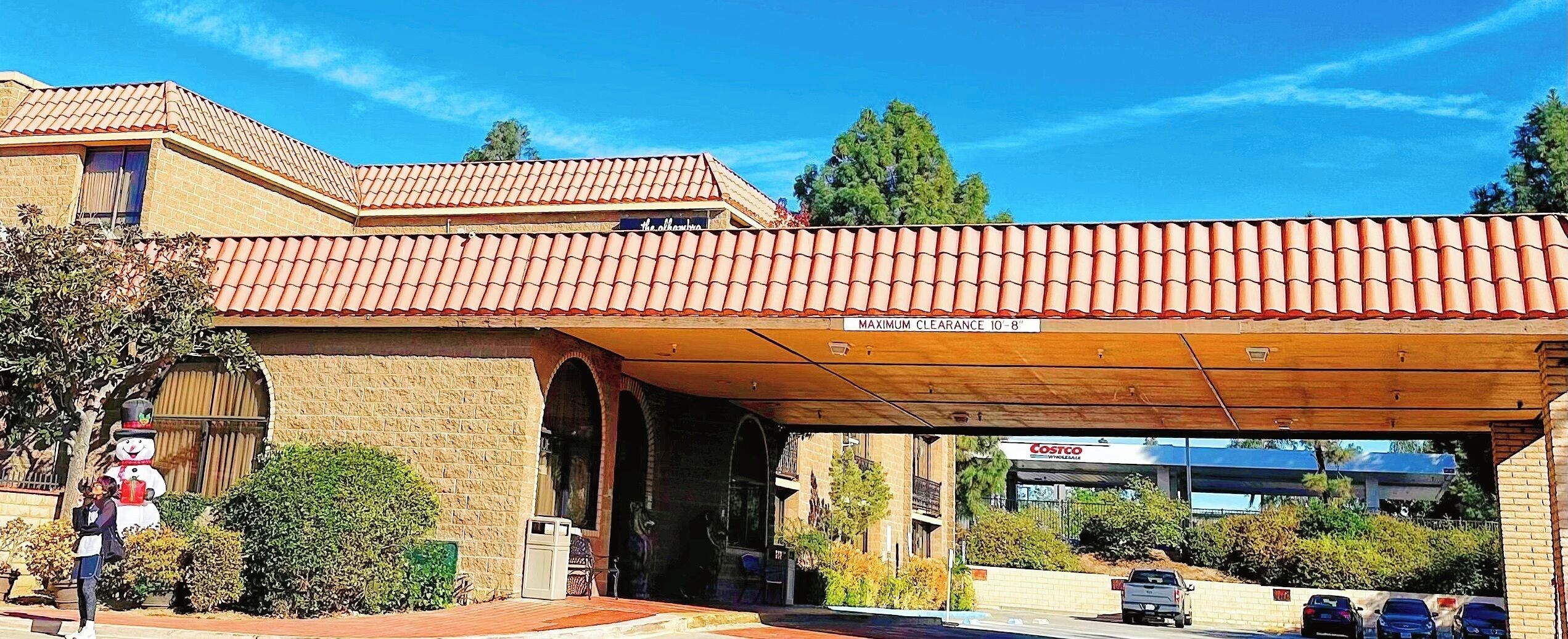 Un edificio con techo de tejas rojas, un letrero que indica la altura máxima permitida y una tienda Costco al fondo.