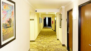 A hotel hallway with a patterned carpet, framed artwork on the walls, and doors on both sides. - Alhambra Hotel (Alhambra)