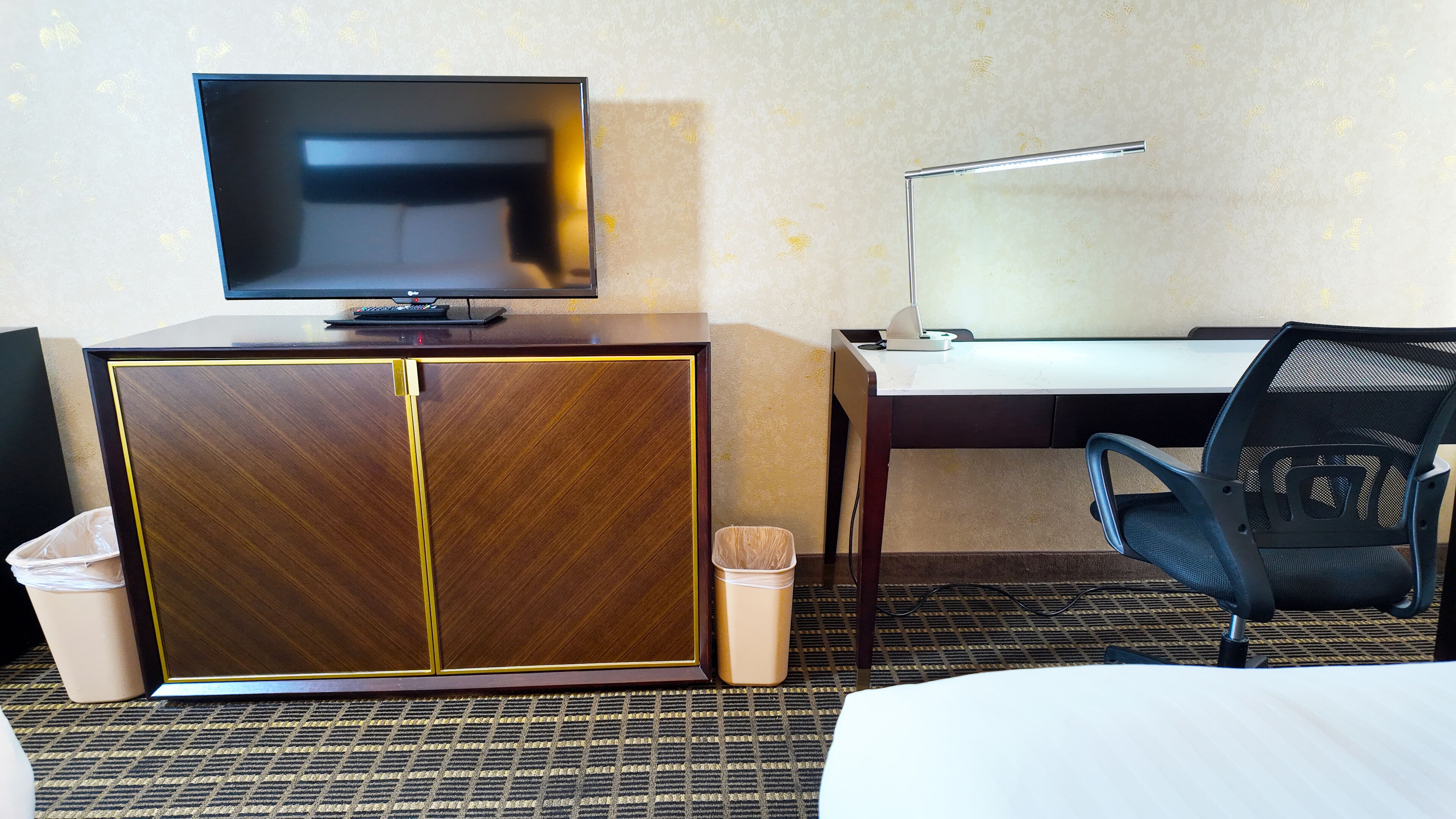 Habitación de hotel con televisión, escritorio, silla y armario.