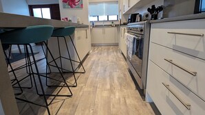 A modern kitchen with a central island, bar stools, and a dining area.