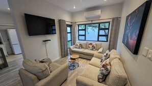 A modern living room with a sofa set, a coffee table, and a flat-screen TV.