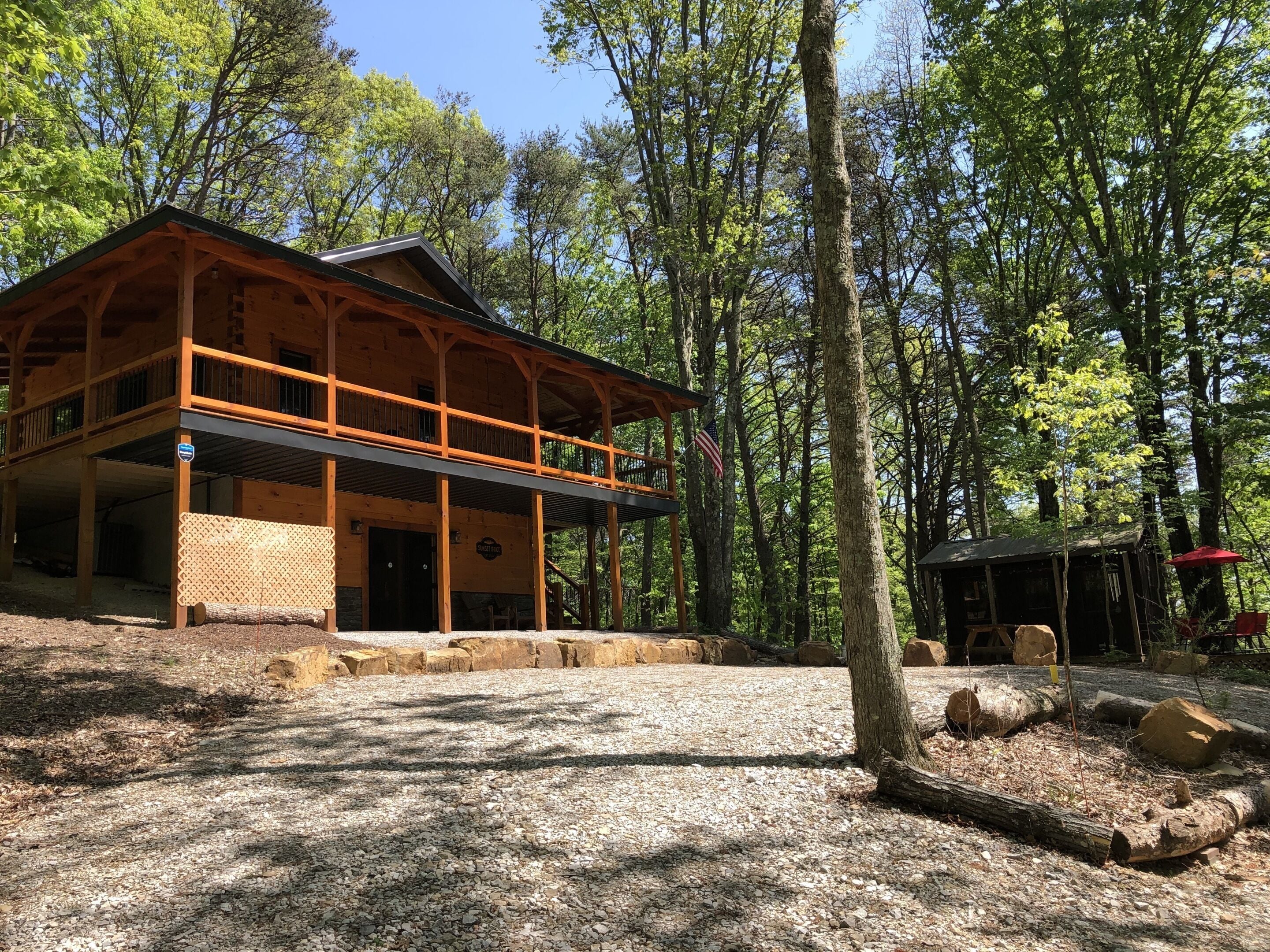 A lodge with a wooden exterior, a covered porch, and a gravel driveway.