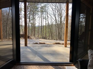 A room with a large window overlooking a forested area.