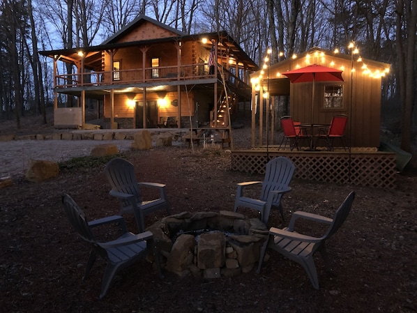 A cabin with a deck, outdoor seating, and a fire pit.