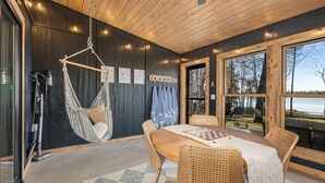 Ein Essbereich aus Holz mit einem Tisch, Stühlen und einem Hängekorbstuhl.