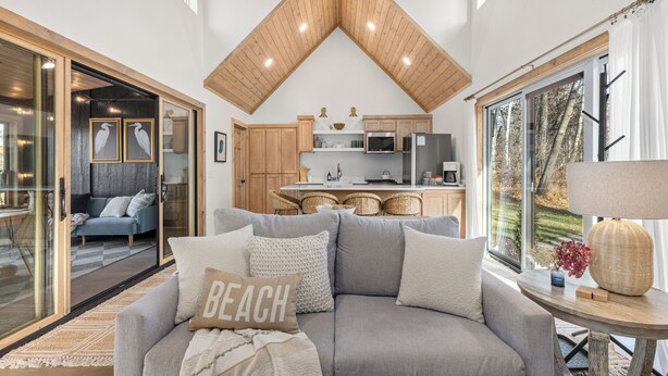 Ein modernes Wohnzimmer mit einem grauen Sofa, einem Couchtisch und Blick auf eine Küche und Essbereich.