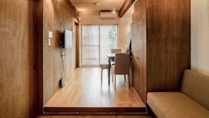 Un couloir étroit avec un plancher en bois, un canapé, une table et des chaises.