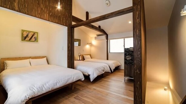 Une chambre avec deux lits, des poutres en bois, un tableau et une fenêtre.