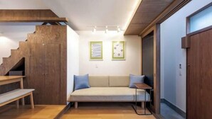 Un intérieur moderne avec un escalier en bois, un canapé avec des coussins, une petite table et deux tableaux encadrés au mur.