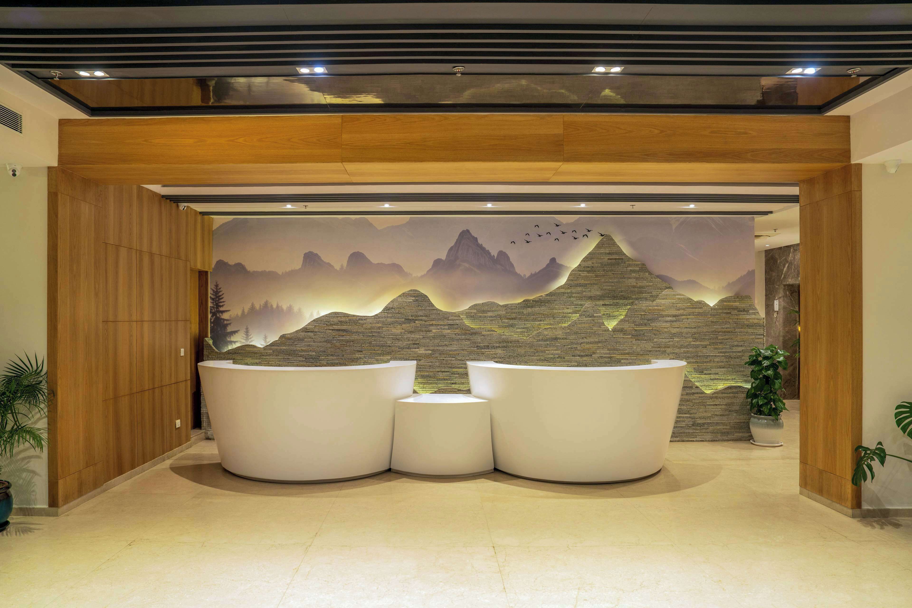 A reception area with a mural of mountains and birds, three white reception desks, and wooden paneling.
