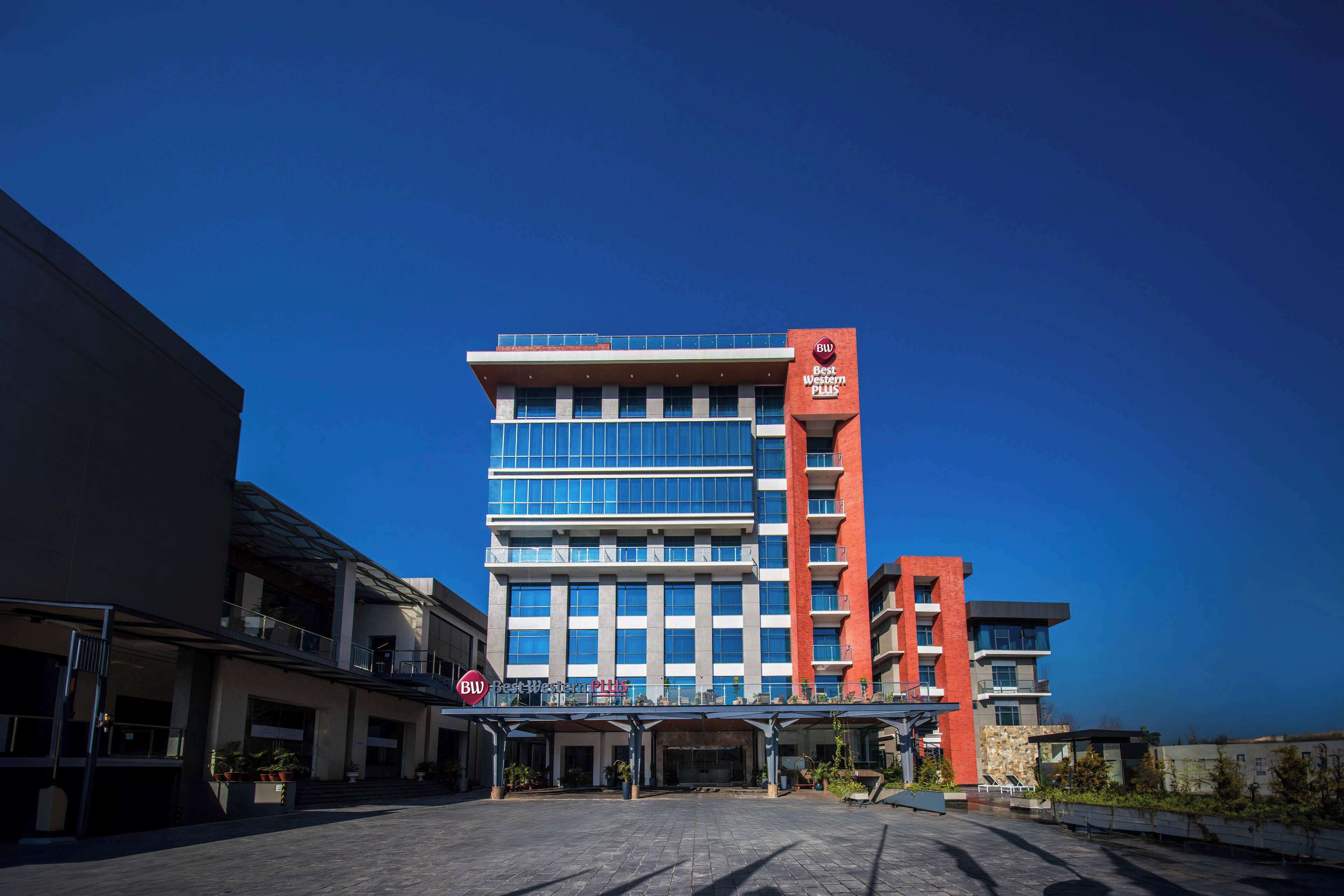 A modern hotel with a prominent red and blue facade, multiple floors, and a covered entrance area.
