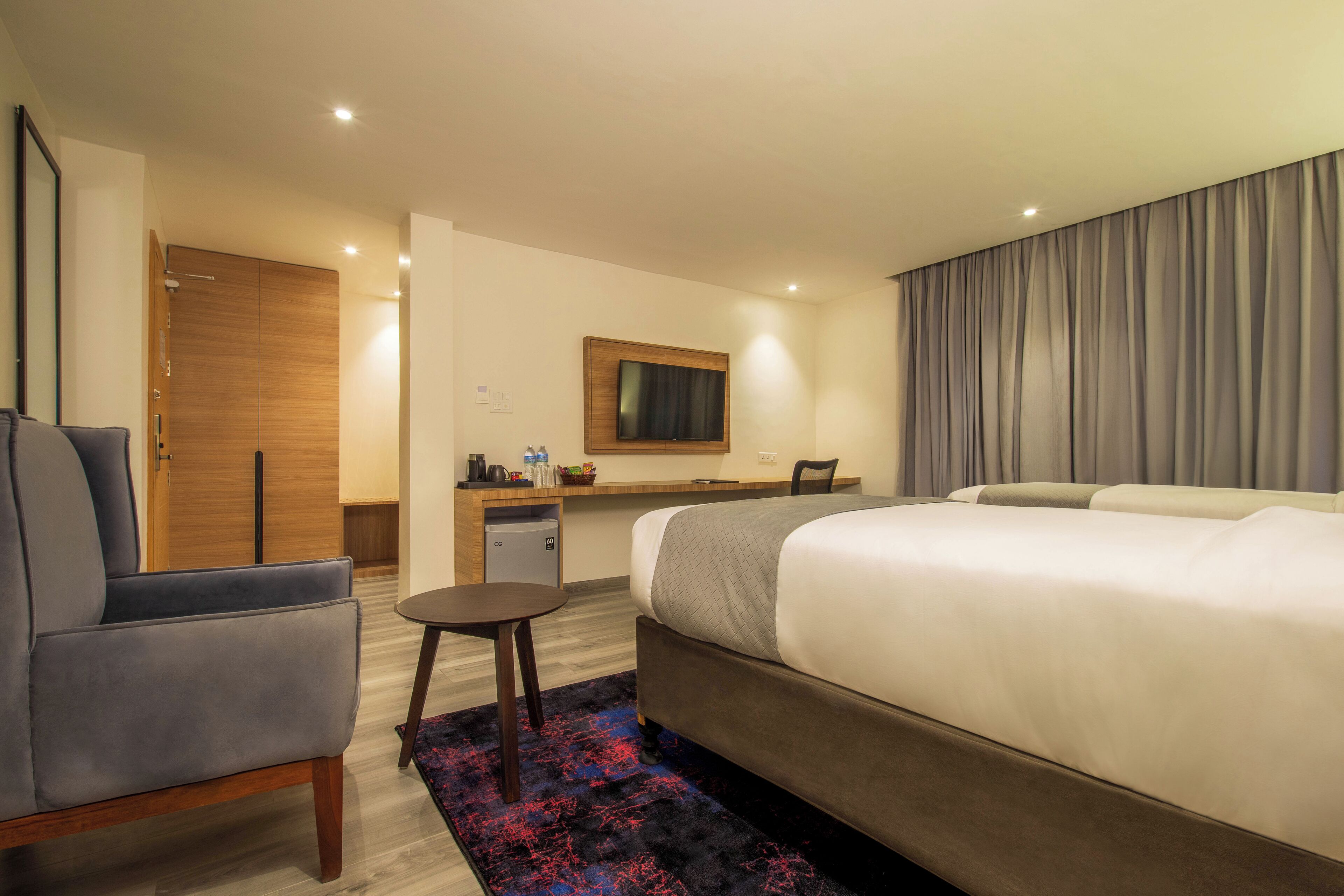 Ein Hotelzimmer mit Bett, Schreibtisch, Stuhl, Fernseher und Kleiderschrank.