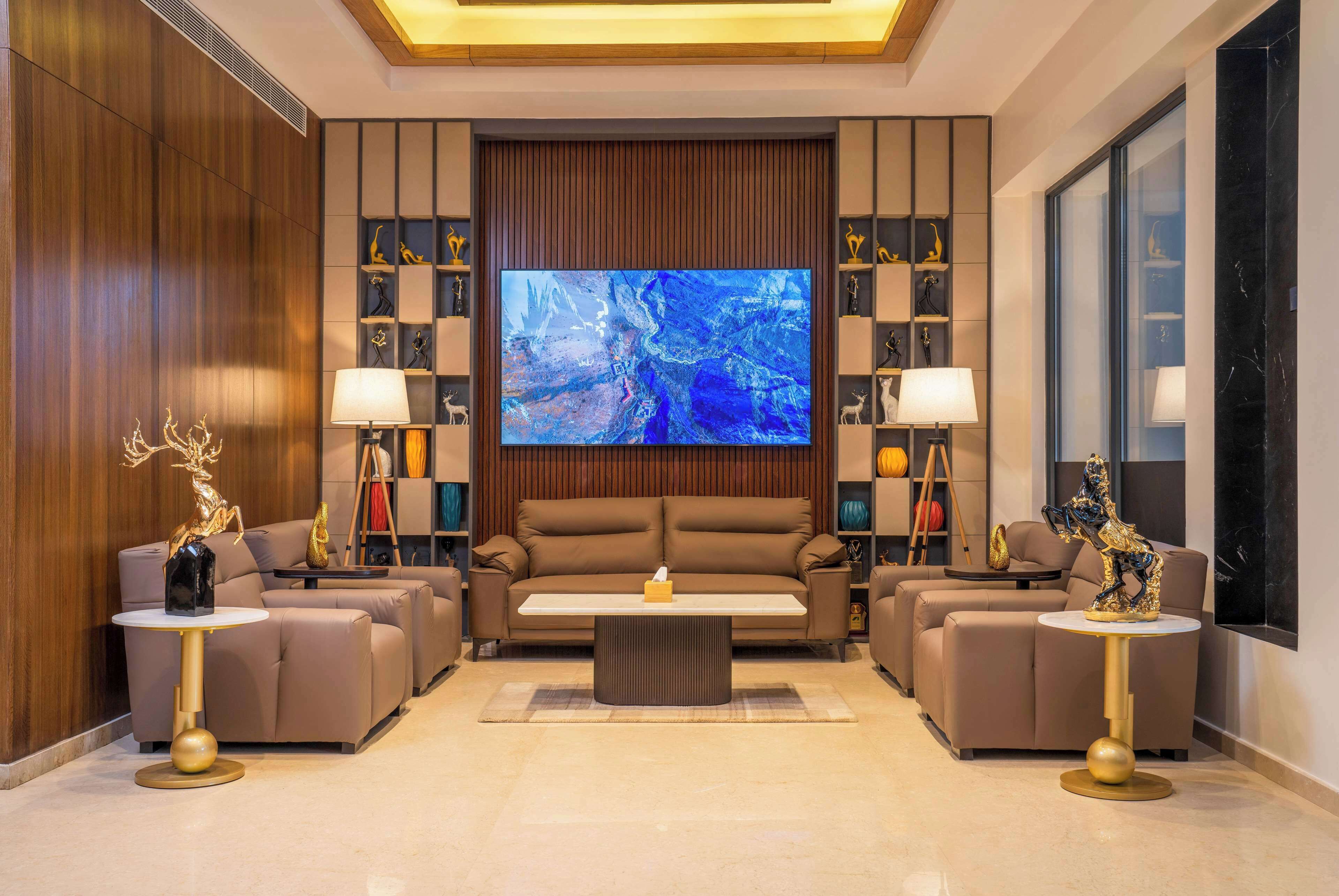 A modern living room with a large flat-screen TV, two sofas, and a coffee table.