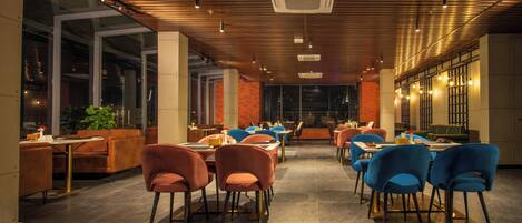 A modern restaurant interior with high ceilings, exposed beams, and a mix of seating styles including booths and tables.