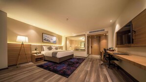 A modern hotel room with a bed, bedside table, lamp, and a desk with a chair. - Best Western Plus Kathmandu Hotel (Kathmandu)