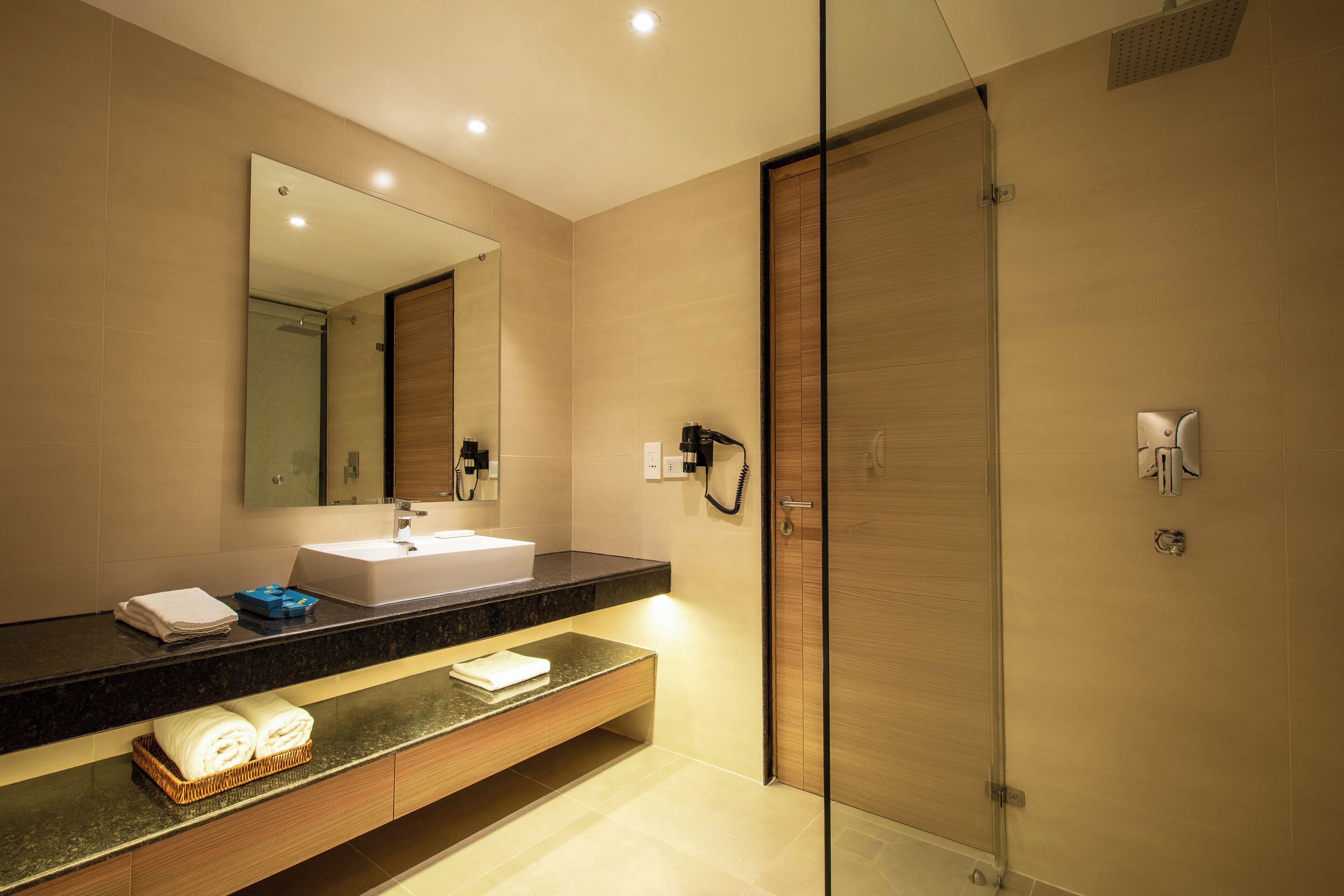 A modern bathroom with a large mirror, a sink, a glass shower enclosure, and a towel rack.