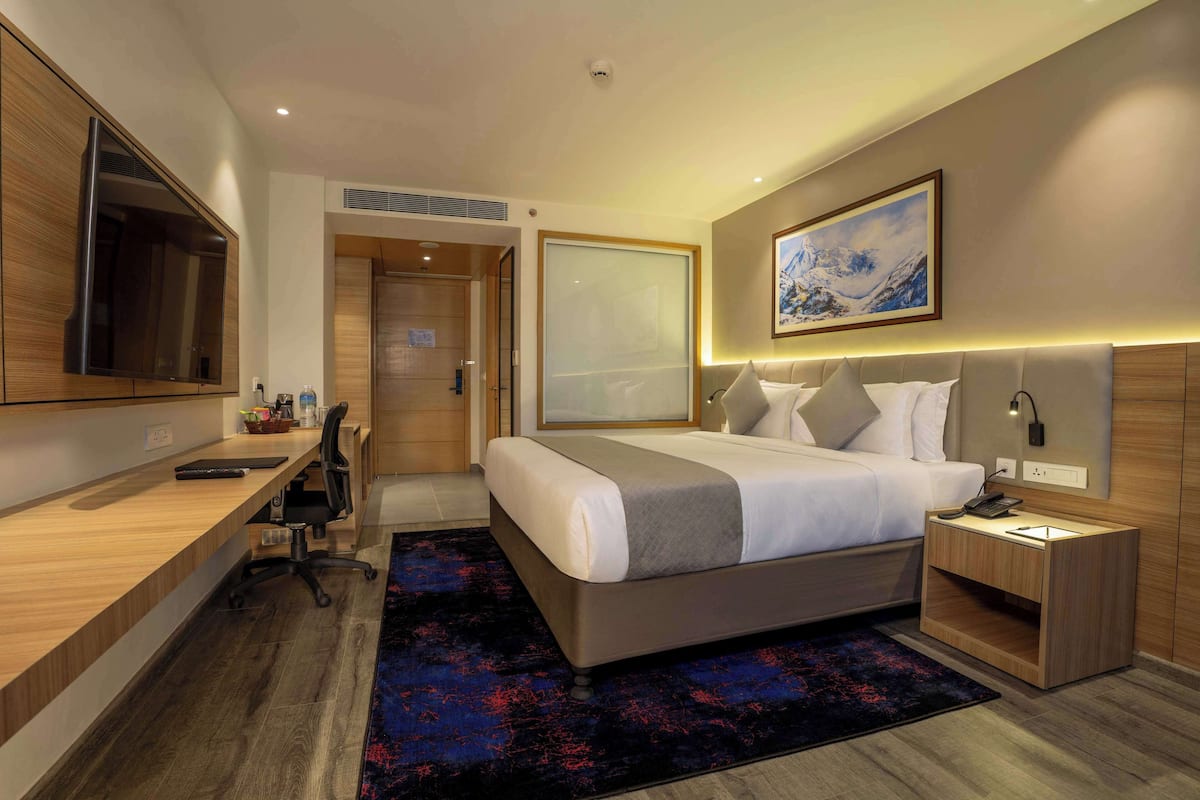A modern hotel room with a bed, desk, and TV.