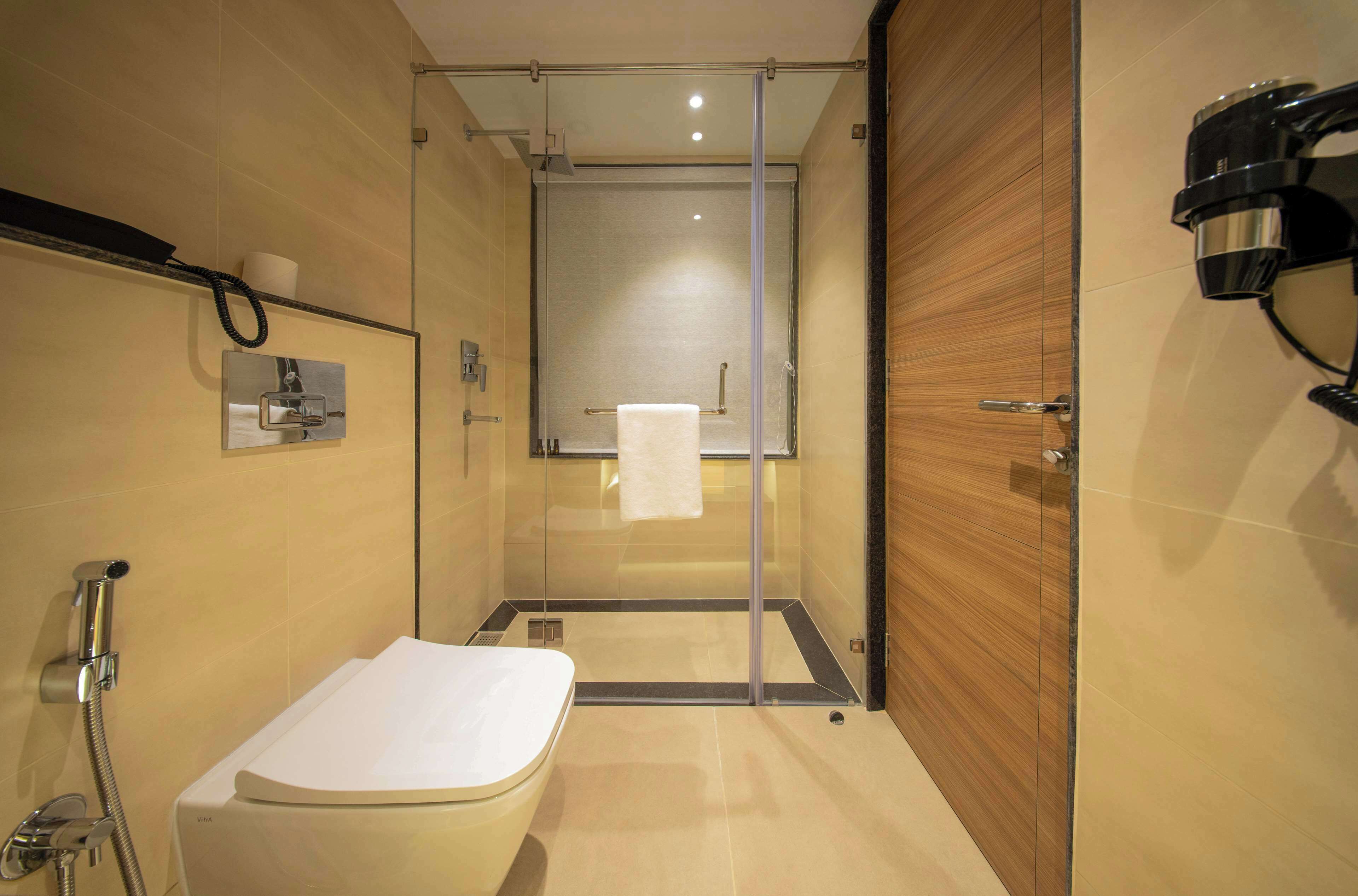 A modern bathroom with a glass-enclosed shower, a standalone bathtub, and a wooden vanity with a towel rack.