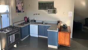 A compact kitchen with a gas stove, sink, and microwave. - Spires Barn Lodge (Christchurch)