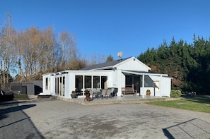A white building with a covered patio area, large windows, and a satellite dish. - Spires Barn Lodge (Christchurch)
