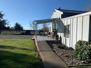 A house with a covered patio area, a lawn, and a gravel path leading to the entrance.
