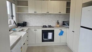 A modern kitchen with white cabinets, a built-in oven, a dishwasher, and a refrigerator. - Quiet house with great views and a 5 min drive to town (Wallan)