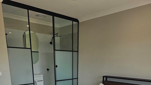 A neatly made bed with white linens and towels, a wooden nightstand, and a sliding glass door closet. - Quiet house with great views and a 5 min drive to town (Wallan)
