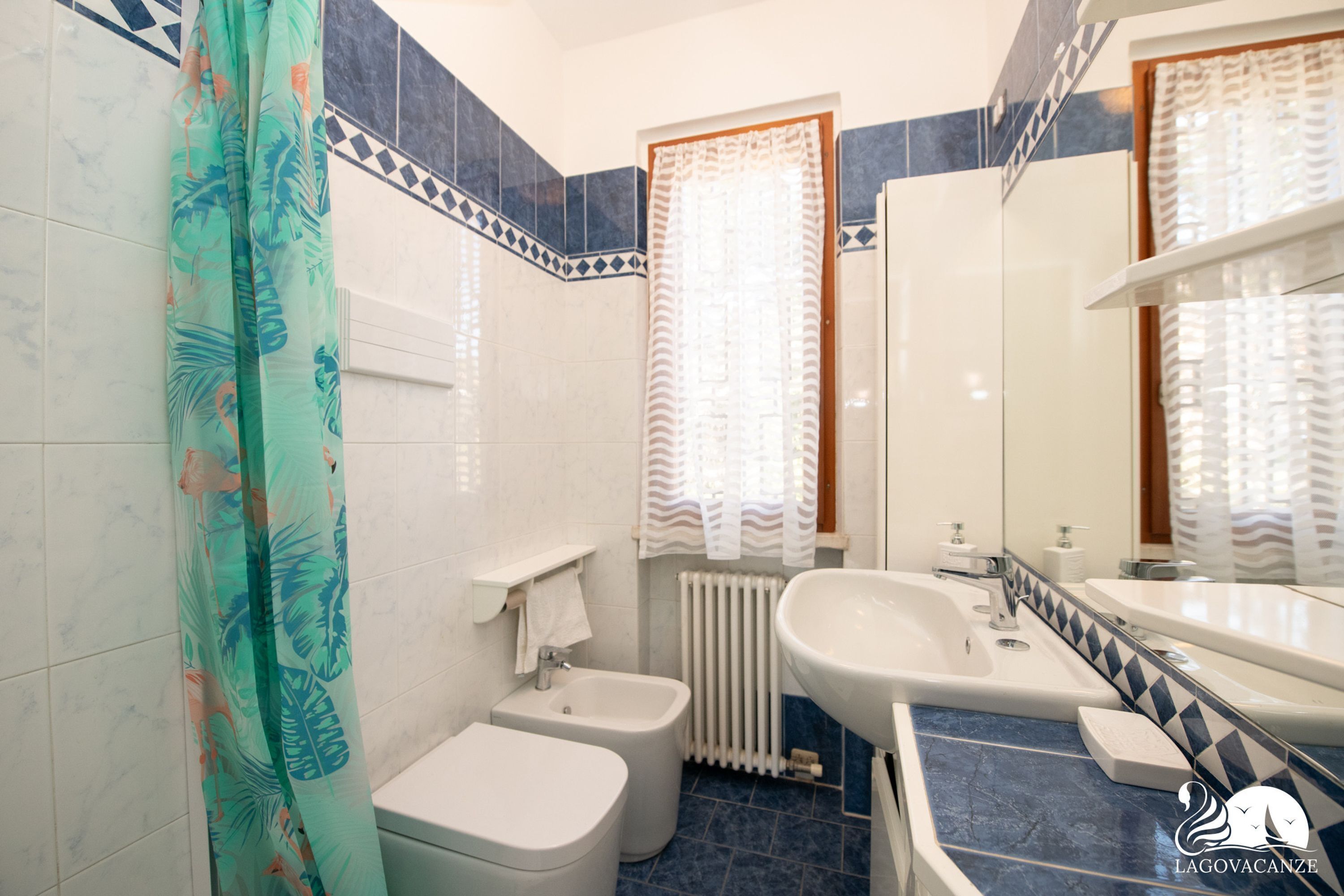 A bathroom with a toilet, bidet, bathtub, and a large mirror.