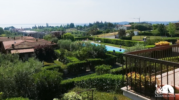 A residential area with a swimming pool, lush greenery, and a view of the sea. - Appartamento Giada in Padenghe sul Garda (Padenghe sul Garda)