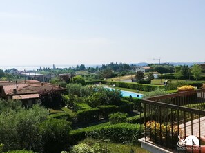 A residential area with a swimming pool, lush greenery, and a view of the sea. - Appartamento Giada in Padenghe sul Garda (Padenghe sul Garda)