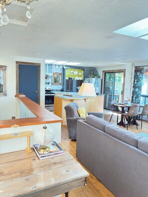 A spacious living room with a wooden coffee table, a grey sofa, and a dining area with a table and chairs.