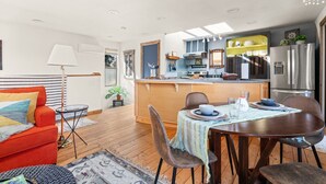 A compact living space with a dining area, kitchen, and a cozy seating area with a sofa and a lamp. - Cozy, comfortable, peaceful, unique lakeside house w beautiful views/Olympia (Lacey)