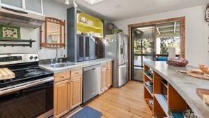 A modern kitchen with a skylight, stainless steel appliances, wooden cabinets, and a large island. - Cozy, comfortable, peaceful, unique lakeside house w beautiful views/Olympia (Lacey)
