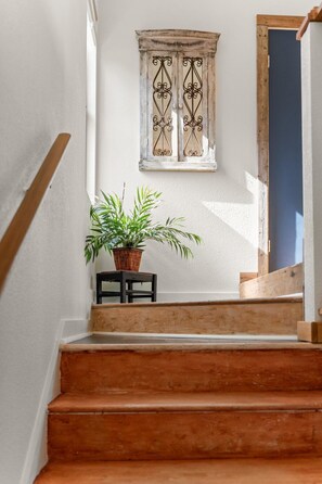 A wooden staircase with a potted plant on a small table at the top.