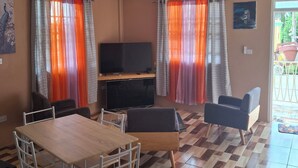 A living room with a TV, a dining table, chairs, and a sofa.