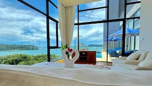 Habitación de hotel con una ventana grande, cama, zona de estar y vista al mar.