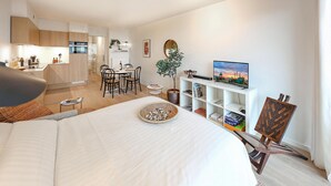 Une chambre d’hôtel moderne dotée d’un grand lit, d’un coin repas, d’une cuisine et d’une télévision.