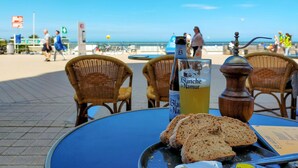 Une table avec une bouteille de Blanche de Namur, un verre contenant un liquide jaune et des tranches de pain.