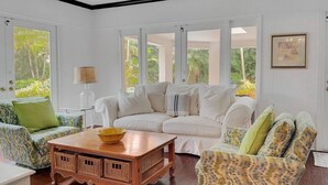 A spacious living room with a white sofa, patterned armchair, and a wooden coffee table.